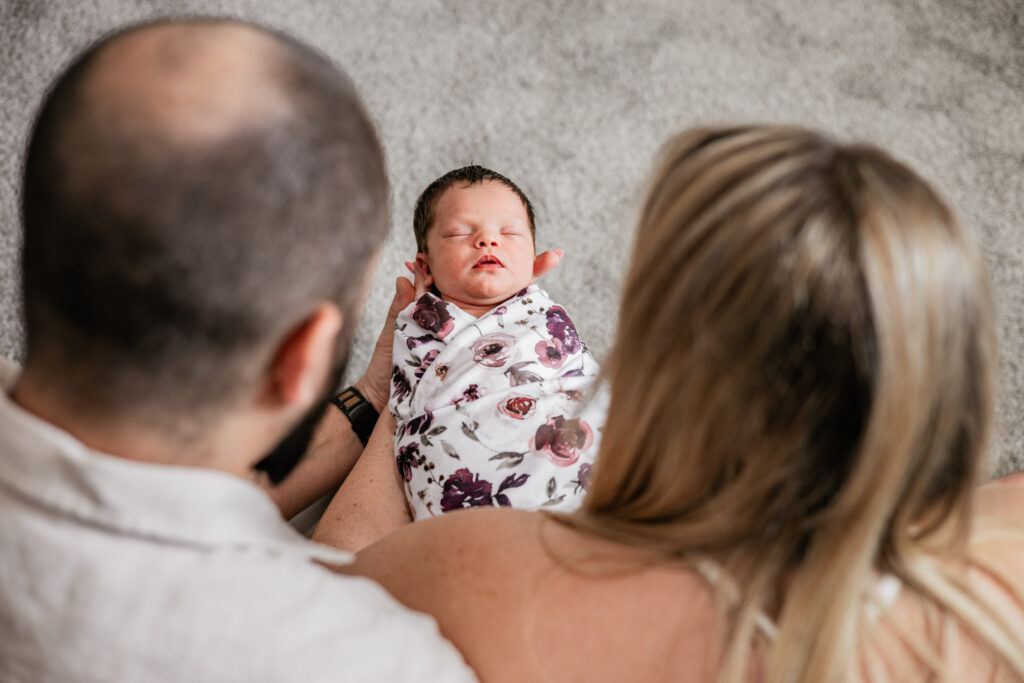 Parents cuddling newborn in natural light family photography